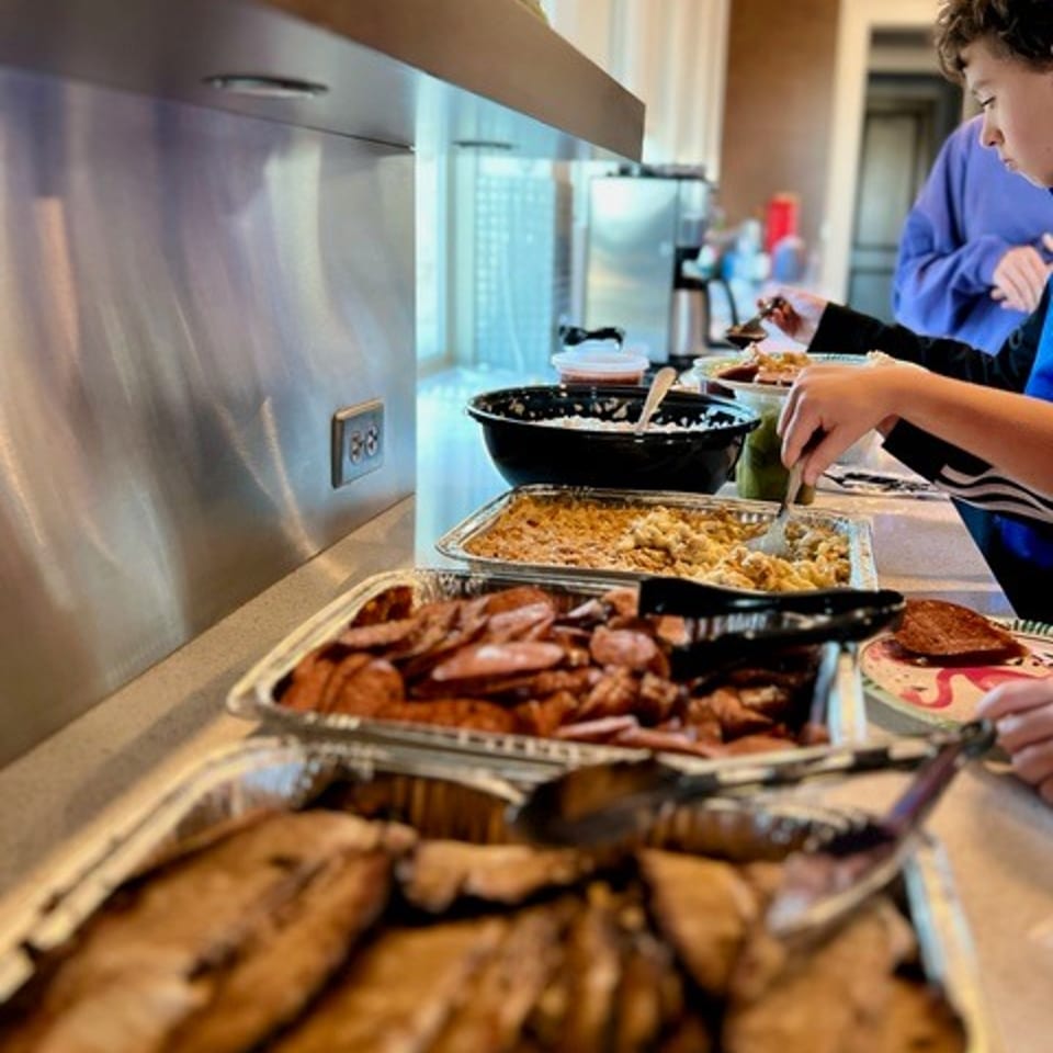 A buffet line with trays of smoked meats, macaroni and cheese, and other dishes.