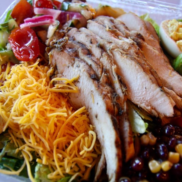 Grilled chicken salad with shredded cheese, deviled egg, tomatoes, and corn and black beans.