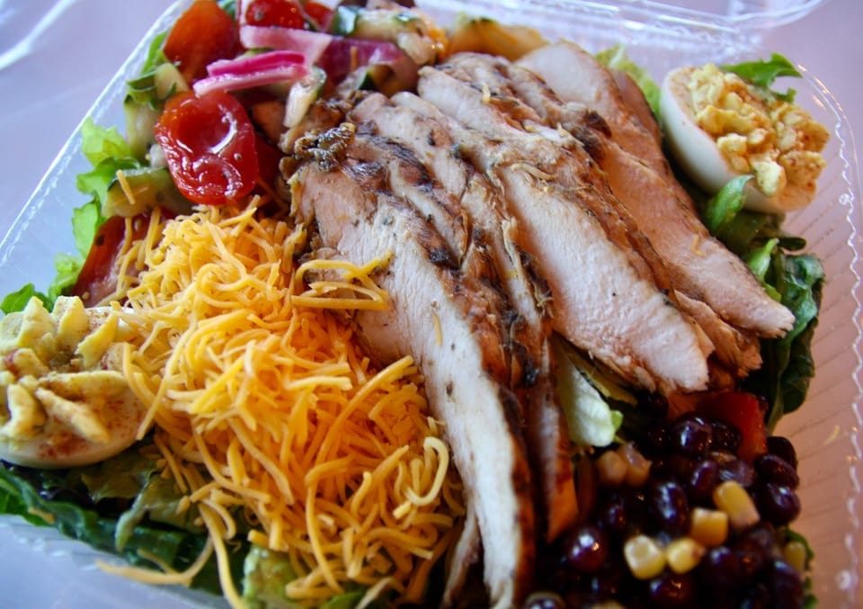 Grilled chicken salad with shredded cheese, deviled egg, tomatoes, and corn and black beans.